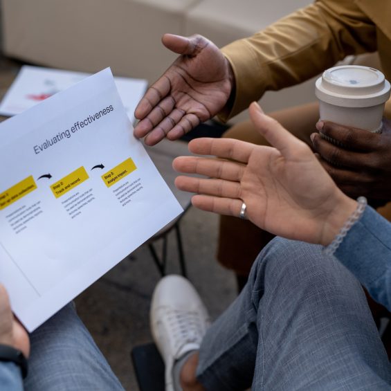 Hands of two intercultural businessmen discussing paper with evaluation data