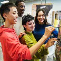 Multiracial students painting inside art room class at university - Focus on center girl face