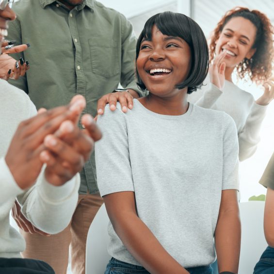 Shot of an attractive young woman sitting while her support group celebrate her success