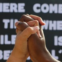 Stronger Together: Image of Caucasian and African American hand locked together.